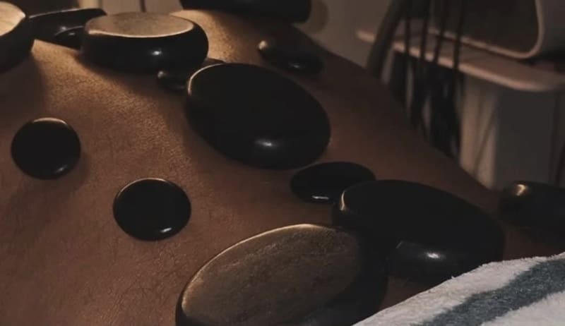 Heated basalt stones laid in a line along a client’s spine